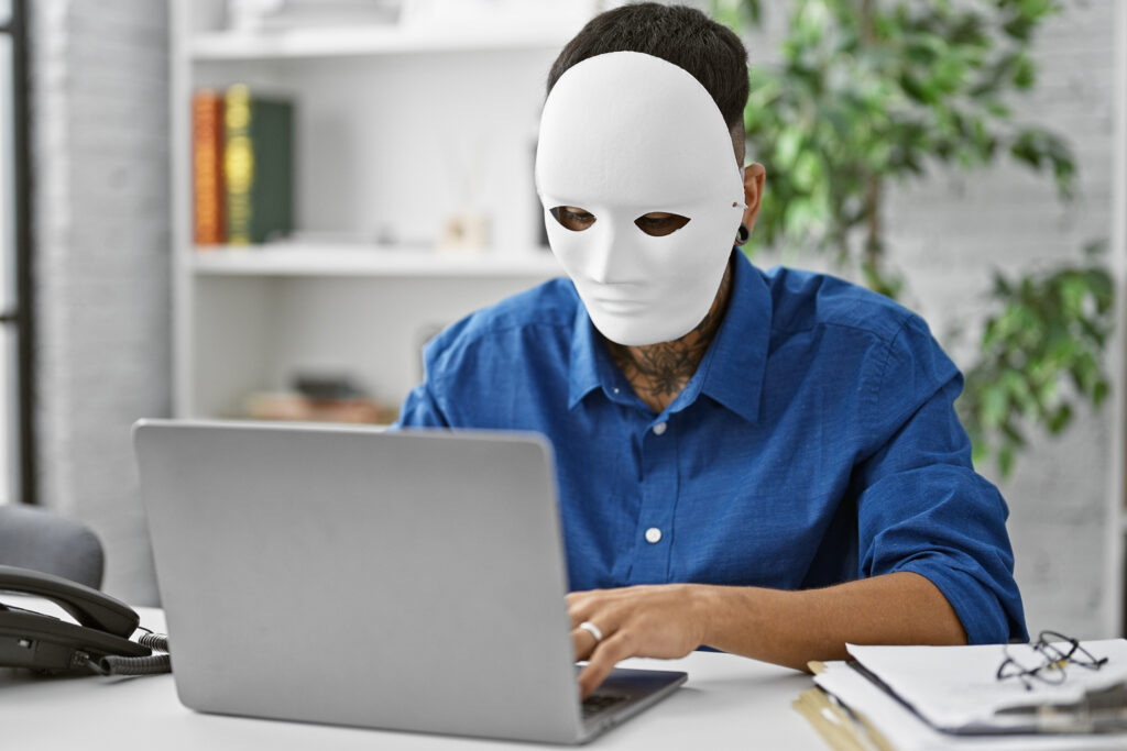 Pseudonymisierung personenbezogener Daten, maskierte Person vor Laptop, Shutterstock / Krakenimages.com